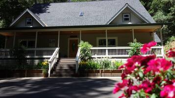 A two-story house with a porch, a small front yard, and a staircase leading to the front door.