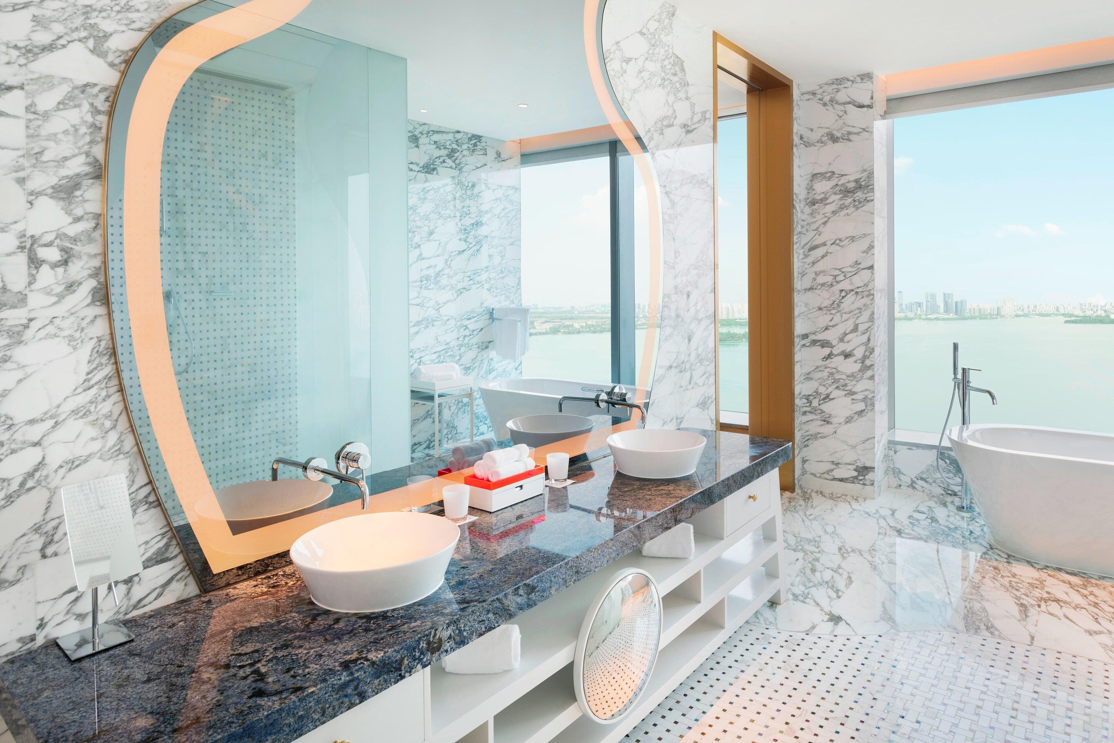 Un baño moderno con dos lavamanos, una bañera y un espejo grande.
