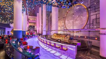 A modern bar area with a curved seating arrangement, a large circular window, and decorative hanging elements.