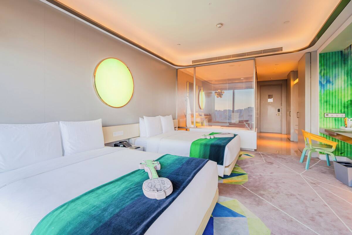 A hotel room with two beds, a desk, and a chair.