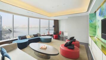A modern living room with a large window, a sofa, a coffee table, and a TV.