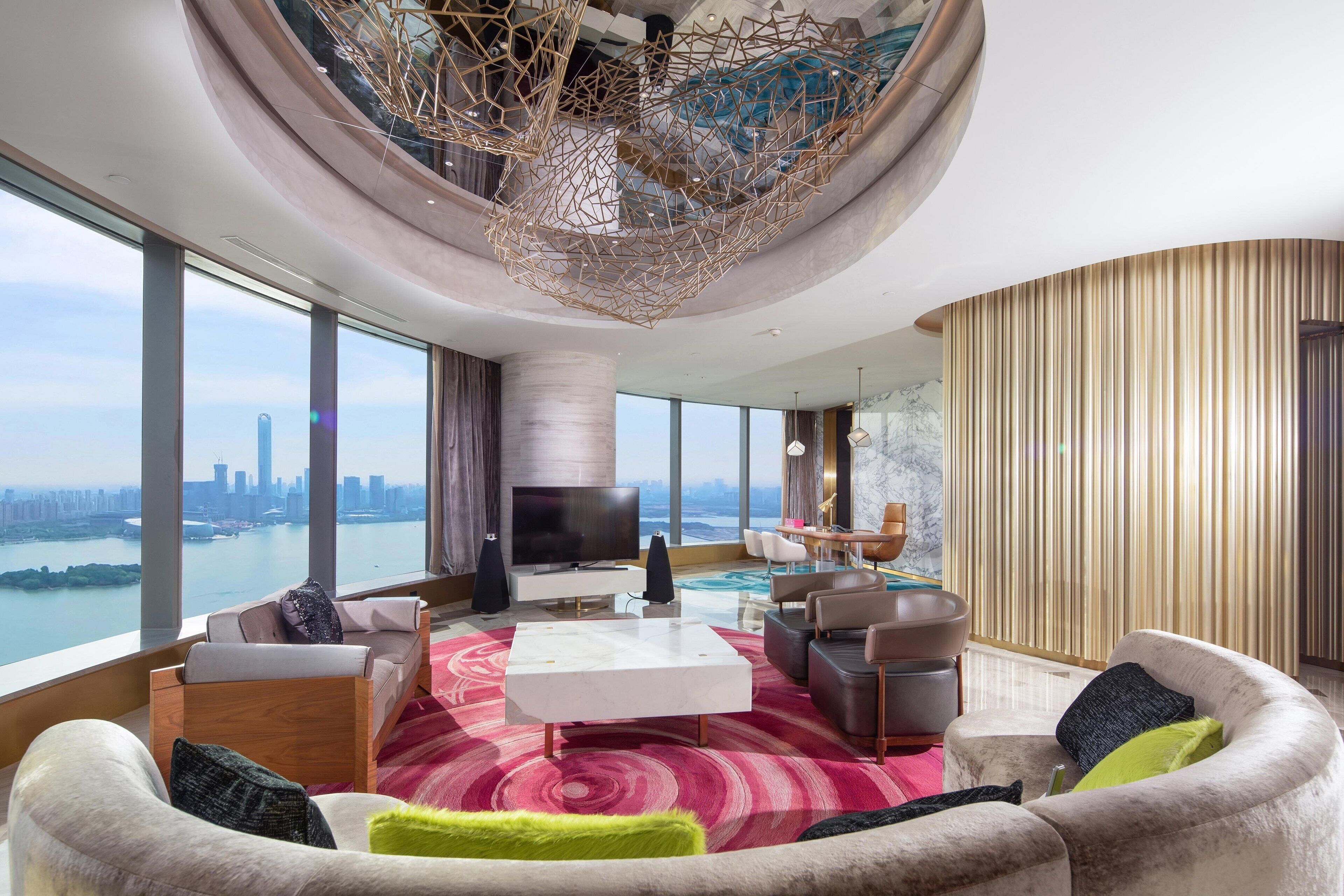 A modern living room with a large TV, comfortable seating, and a view of a cityscape.