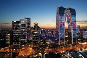 A cityscape at dusk with modern skyscrapers, including a prominent building with a unique arch design. - W Suzhou (Suzhou)