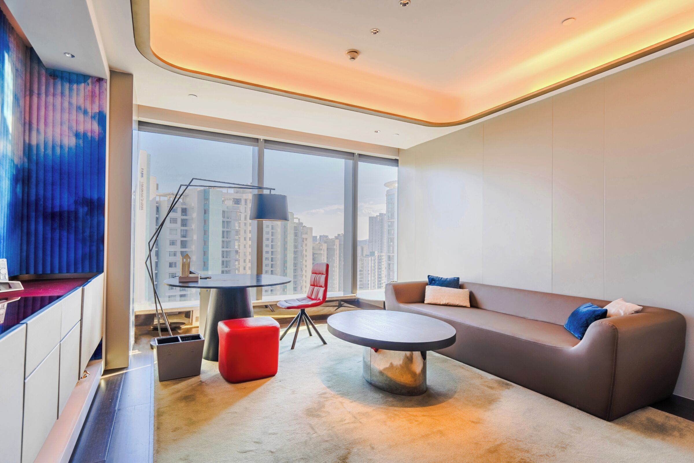 A modern living room with a sofa, red chair, and a round coffee table.