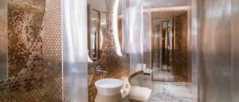 Un baño moderno con un espejo grande, un lavamanos redondo y un suelo de mármol.