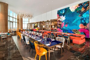 A spacious dining area with long tables, colorful chairs, and a vibrant mural on the wall. - W Suzhou (Suzhou)
