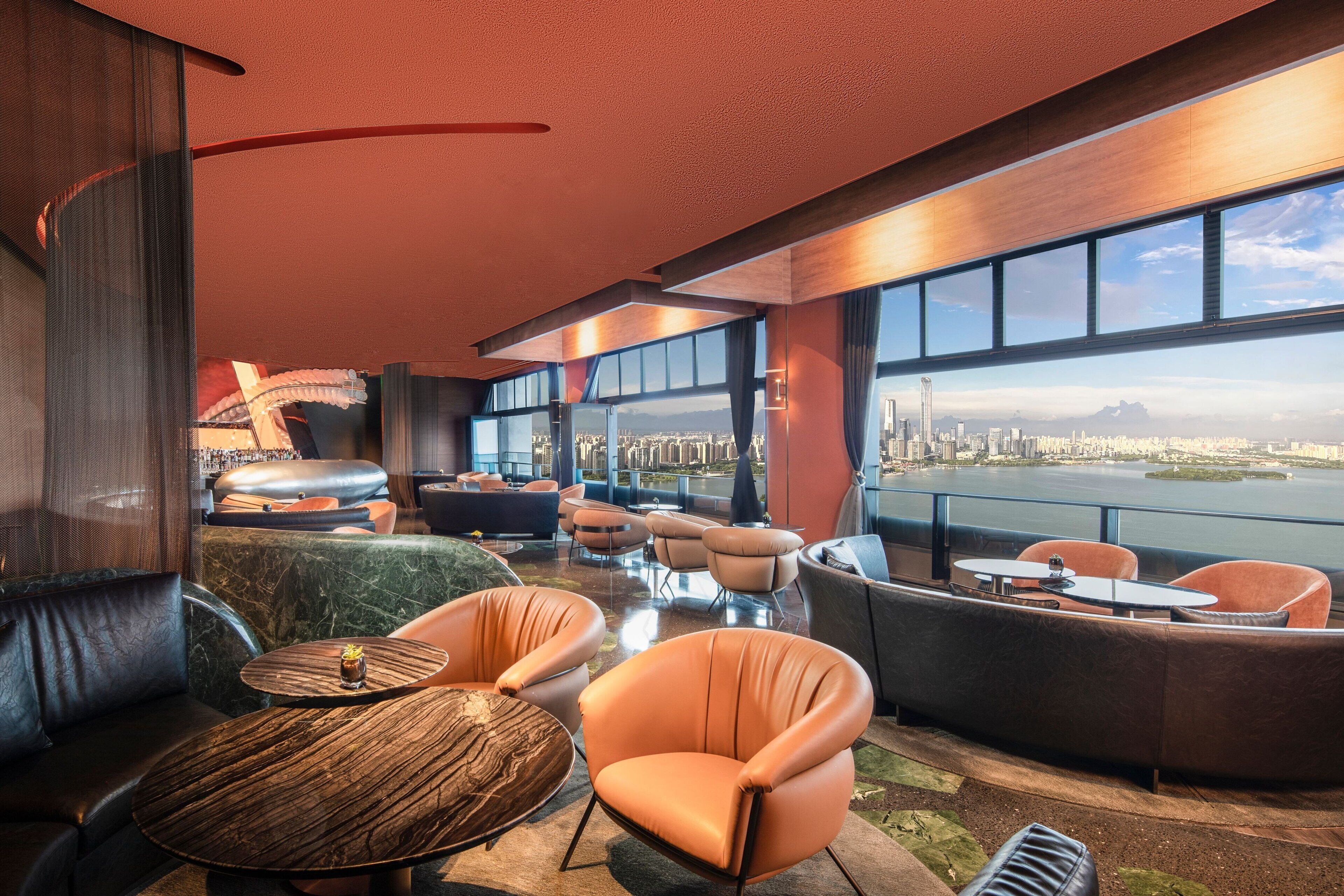 Una sala lounge moderna con sedute in pelle, vista sulla città e un'ampia finestra che si affaccia su un corpo d'acqua.