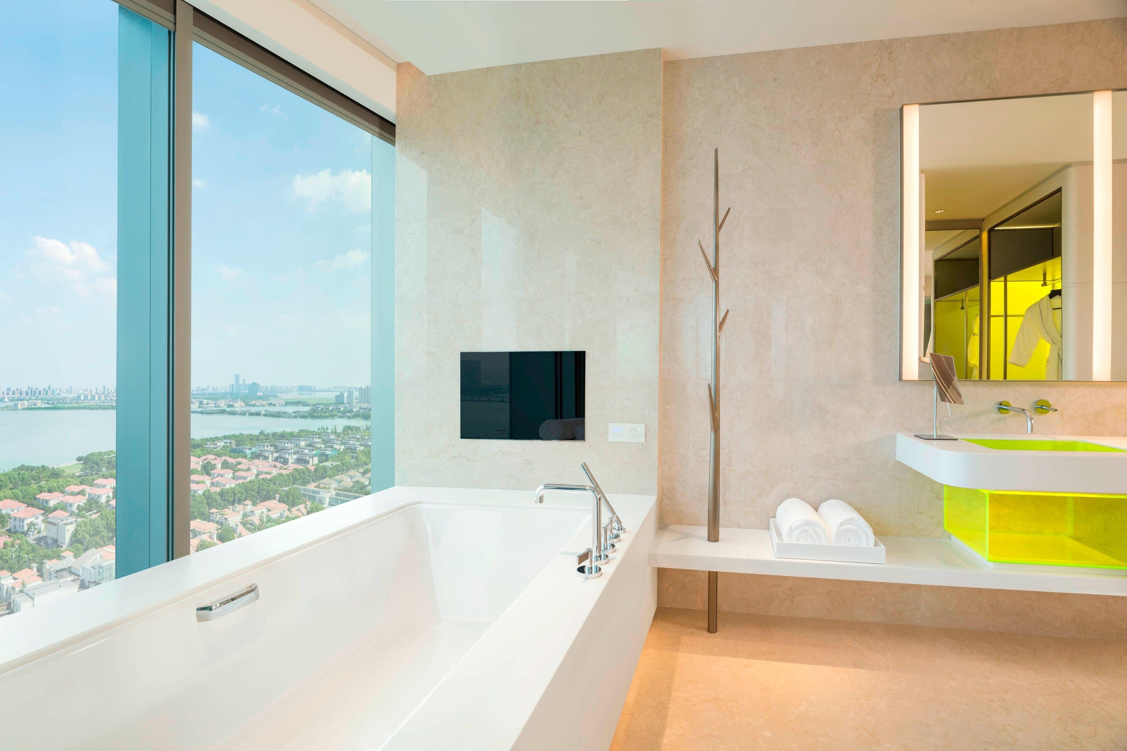 Une salle de bain moderne avec une grande baignoire, un lavabo doté d’un receveur vert et un grand miroir.