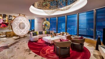 A modern hotel lobby with a large seating area, a decorative ceiling, and a city view.