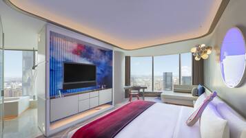 Une chambre d’hôtel moderne dotée d’un grand lit, d’un téléviseur fixé au mur, d’un coin salon avec vue sur la ville et d’une grande fenêtre.