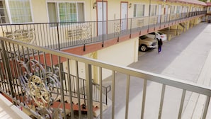Ein Motel mit überdachtem Parkplatz und einem Balkon mit aufwendig gestalteten Metallgeländern.