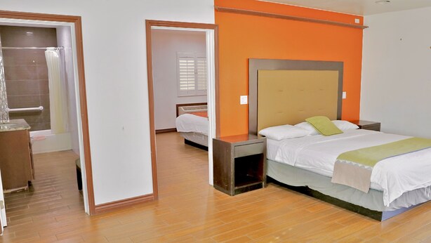 Ein Hotelzimmer mit Bett, Nachttisch und einem durch eine offene Tür einsehbaren Badezimmer.