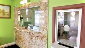 Ein Empfangsbereich mit einer Marmor-Apotheke, einer Pinnwand und einer Glastür mit Sucher.