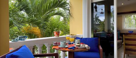 A balcony with a table set for breakfast, a chair, and a view of the outdoors.