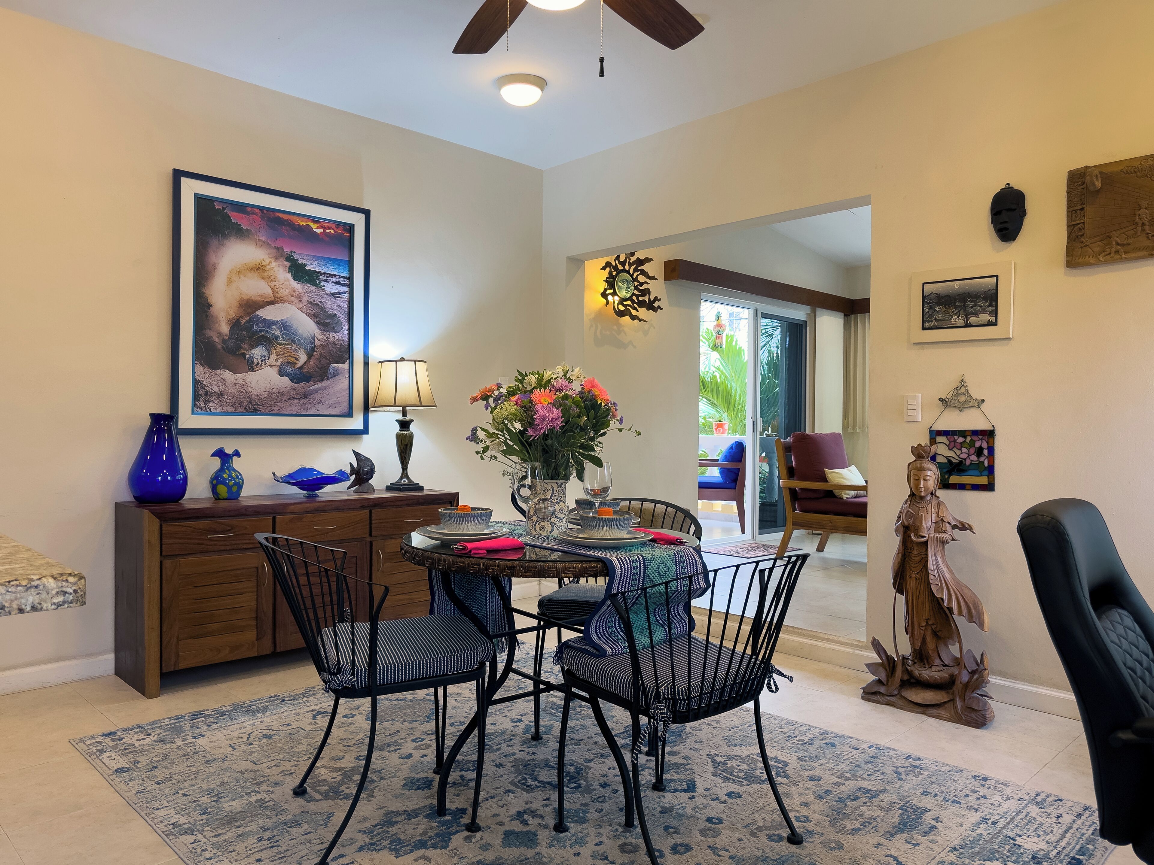 Un coin repas comprenant une table, des chaises, un vase de fleurs et un tableau accroché au mur.