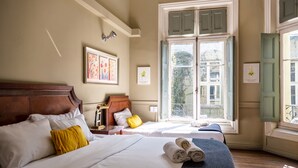 Una habitación de hotel con dos camas, un ventanal grande y obras de arte en las paredes.