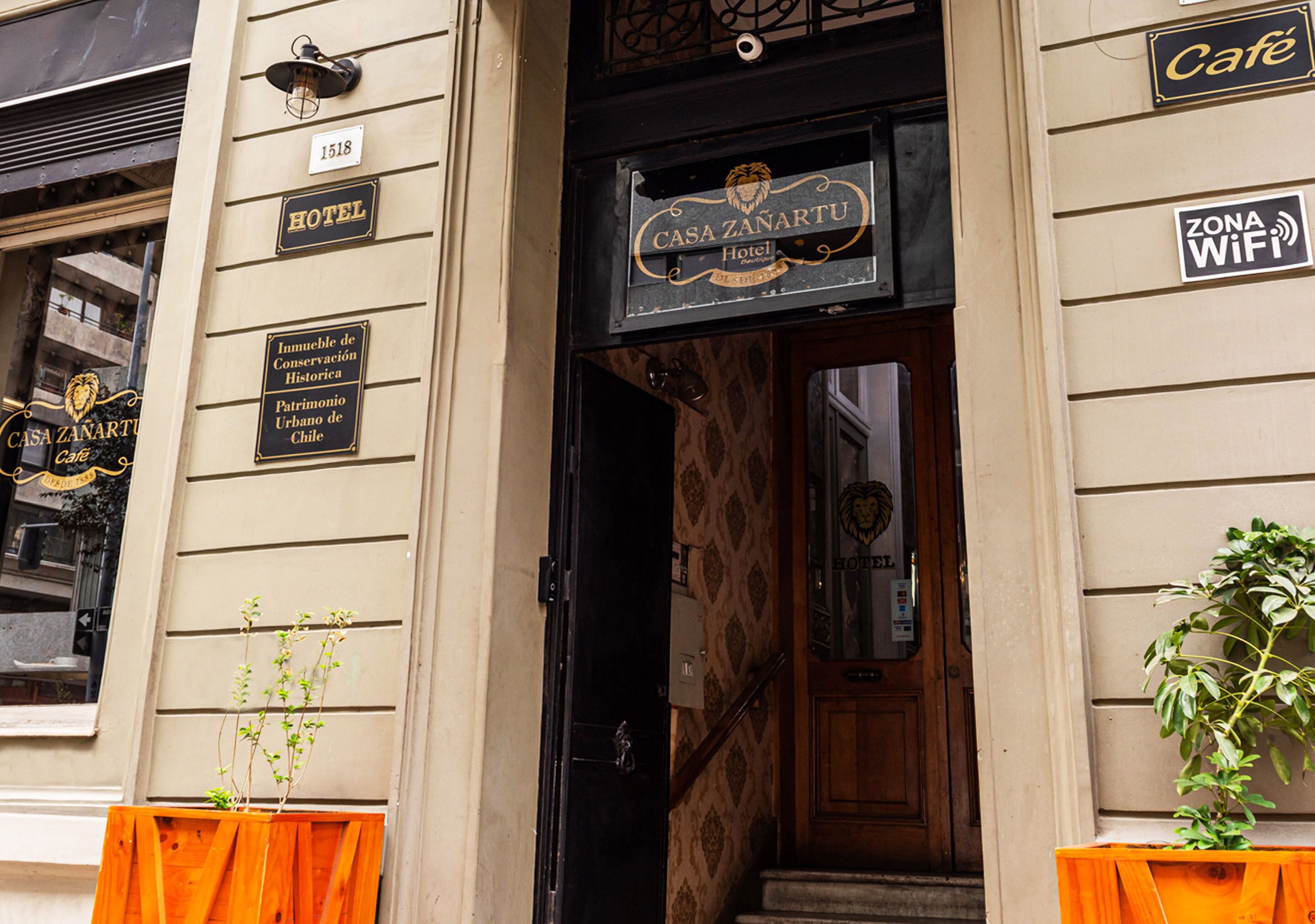 A hotel entrance with a sign for 'Casa Zanartu Hotel' and a 'Zona WiFi' sign.