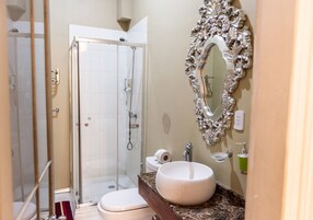 Une salle de bain avec une douche à parois de verre, un lavabo blanc et un grand miroir décoratif.