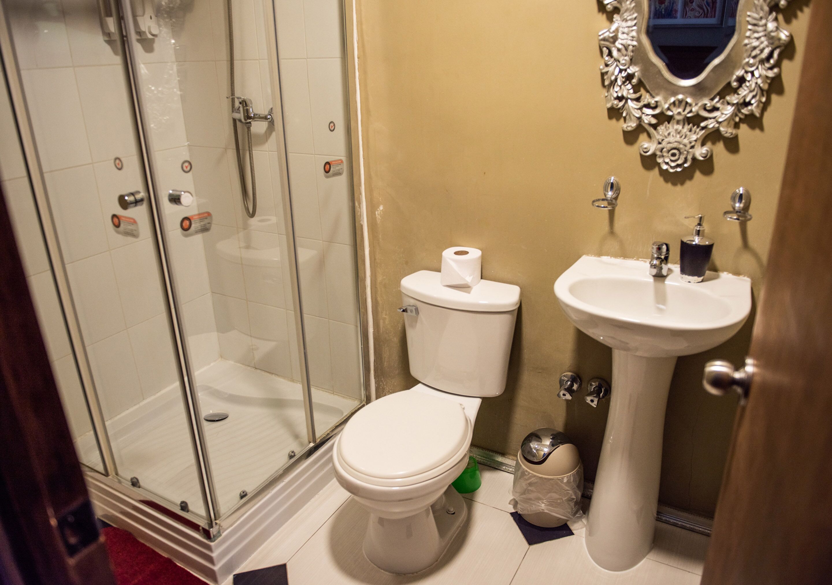 Un baño con ducha de vidrio, inodoro y lavamanos pedestal.