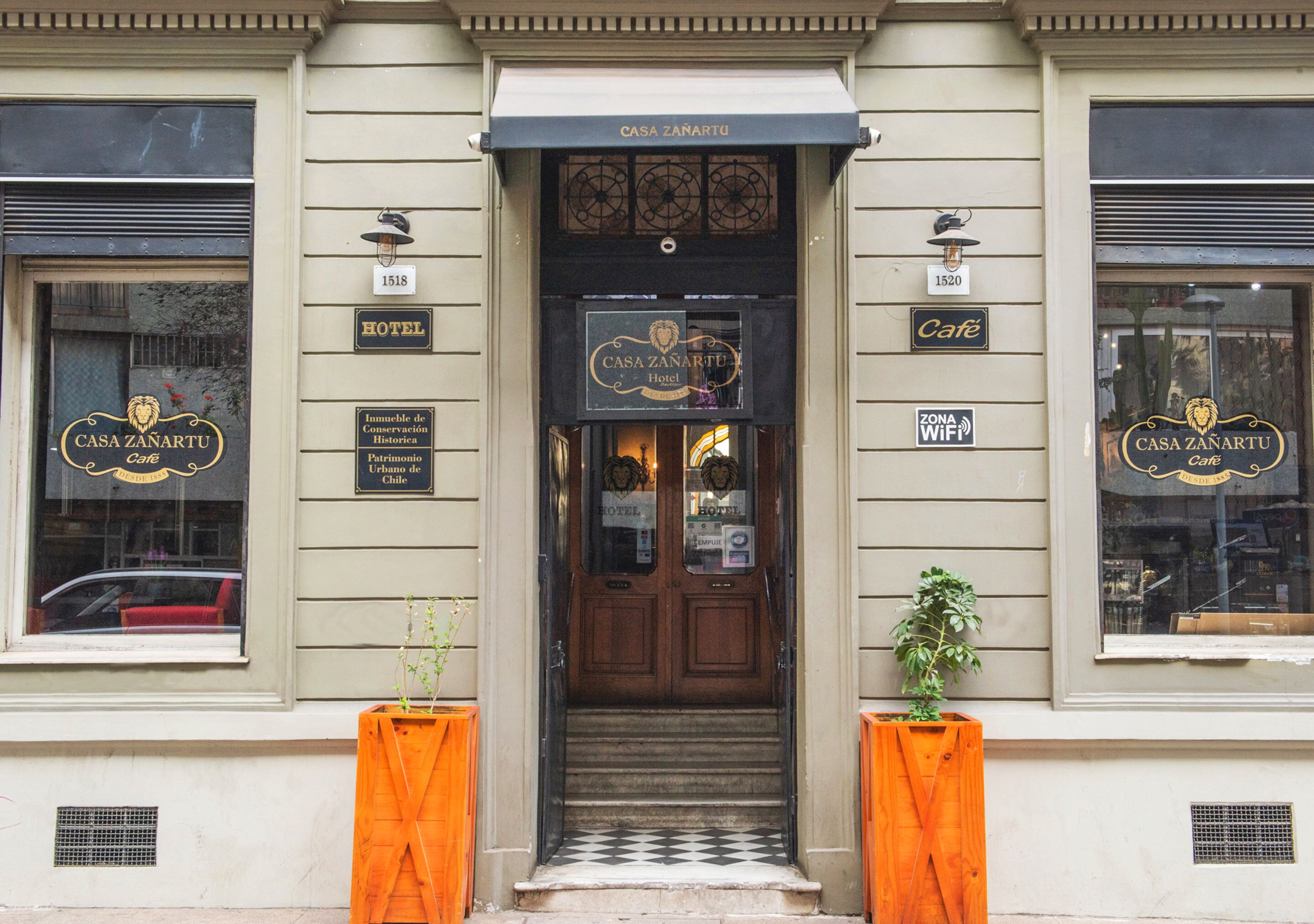 La entrada del Hotel Casa Zanartu, con piso a cuadros, puertas de madera y dos macetas naranjas.