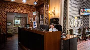 A reception desk with a wooden finish, a clock, framed pictures, and a television screen.