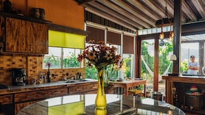 Una cocina con armarios de madera, una mesa de vidrio y un jarrón con flores.