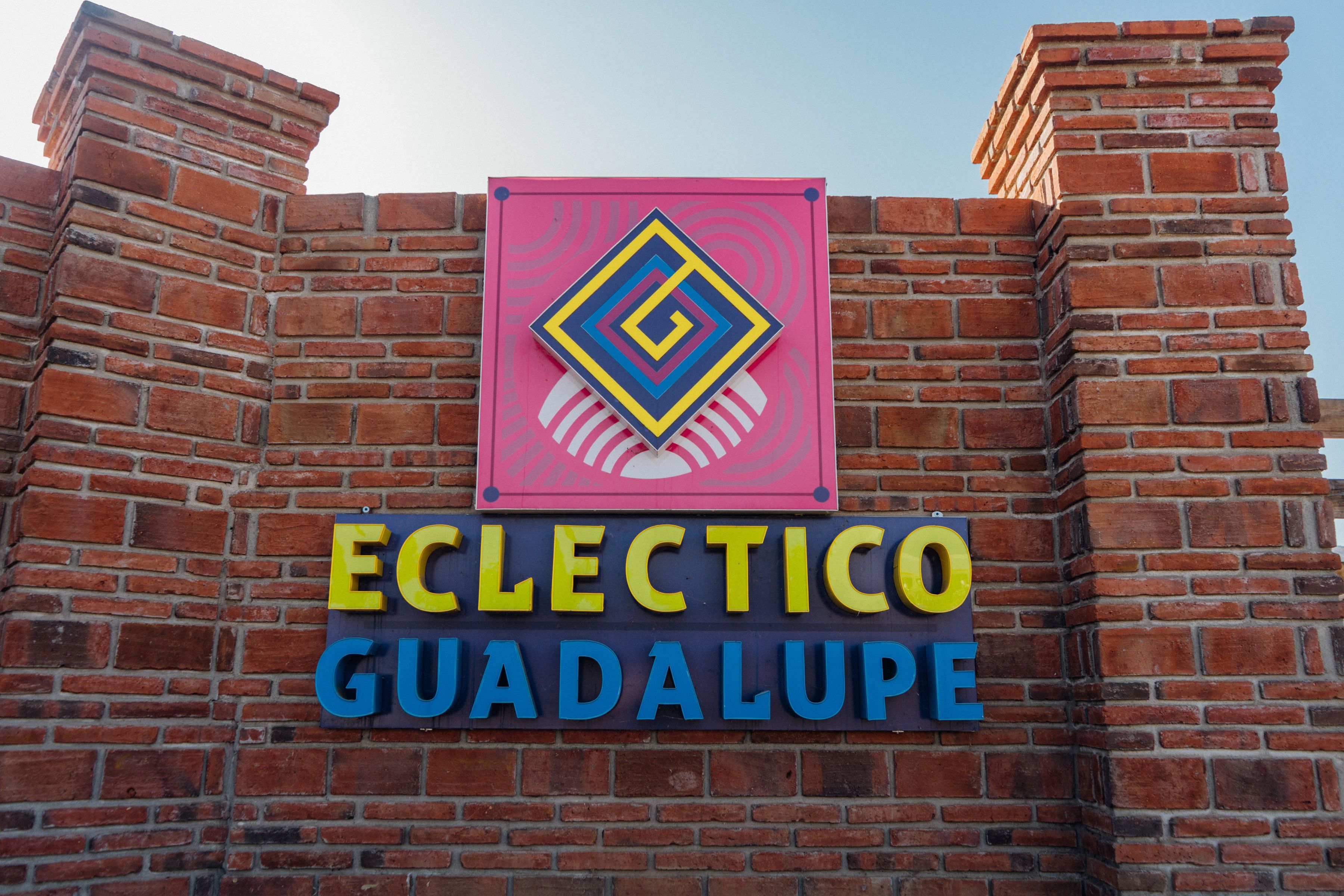 Eine Ziegelwand mit einem Schild, auf dem 'ECLECTICO GUADALUPE' steht.