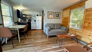 A compact living space with a kitchenette, a sofa, a dining table, and a wooden wall.