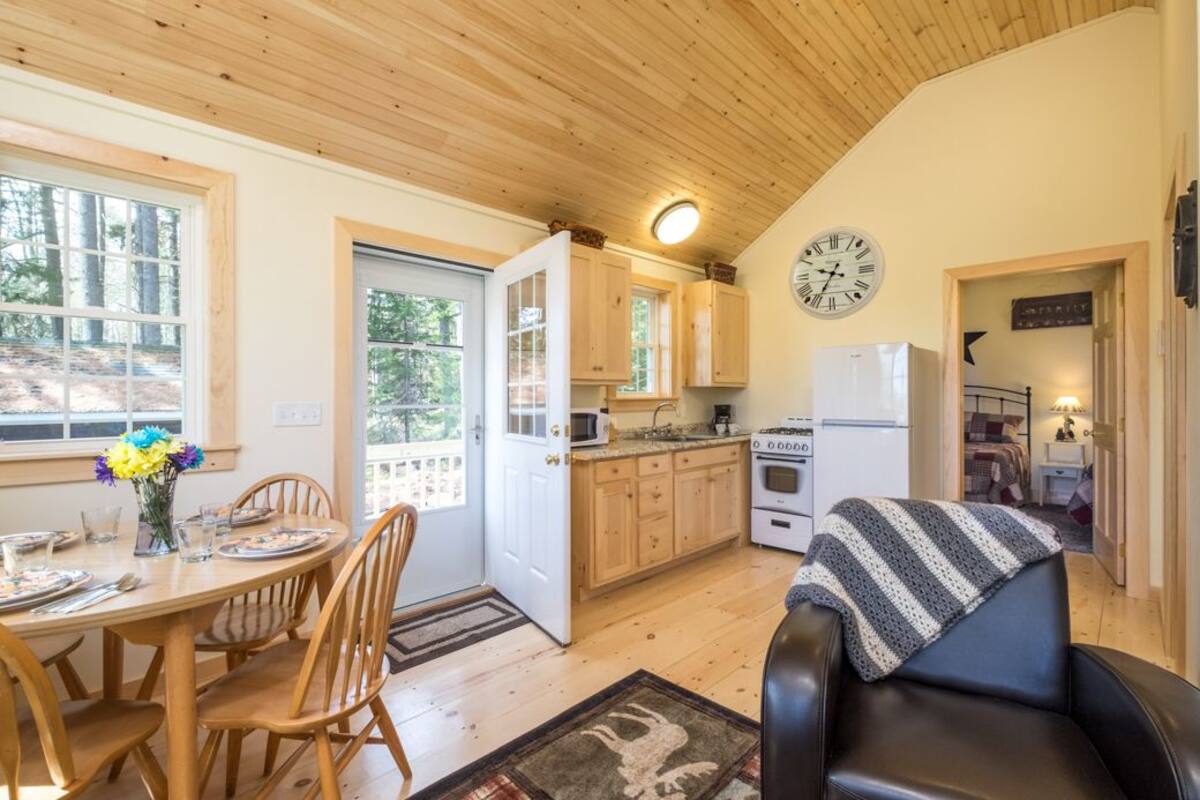 A cozy cabin interior with a dining area, kitchen, and living space.