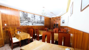 A dining area with wooden paneling, tables with yellow tablecloths, and chairs. - Hotel El Turista (Arequipa)