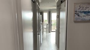 A hallway with a patterned floor, a dining area with a table and chairs, and a door leading to a balcony.