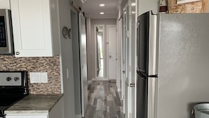 A kitchen with a stainless steel refrigerator, white cabinets, and a herringbone-patterned floor.