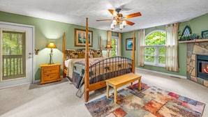 A four-poster bed with a wooden headboard, a ceiling fan, a fireplace, and a view of the outdoors through a window. - 1 Bedroom, Sleeps 4, Minutes To Downtown Gatlinburg, Pool Table (Gatlinburg)