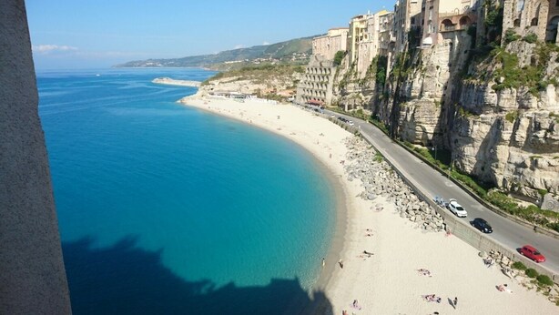 A coastal view with a beach, rocky cliffs, and buildings along the shoreline. - Stunning studio holiday apartment for 2/3 on resort, close to beach with 2 pools (Pizzo)