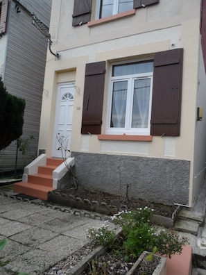 Ein Wohnhaus mit einer weißen Tür, braunen Fensterläden und einem Fenster mit weißem Rahmen.