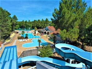 A resort with multiple swimming pools, a water slide, and lounge areas surrounded by trees. - 131. 2 bedroom mobile home (Saint-Jean-De-Monts)