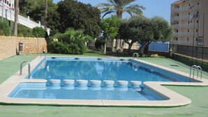 A rectangular swimming pool with a tiled edge and a green deck surrounding it. - Nice apartment 500 meters from the beach, Pool, Parking, Wi-Fi, Satellite TV (SANTA POLA)