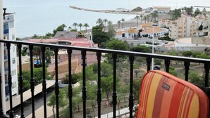 A balcony with a view of a coastal town, including buildings, a beach, and palm trees. - Nice apartment 500 meters from the beach, Pool, Parking, Wi-Fi, Satellite TV (SANTA POLA)