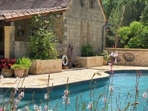 A pool area with a stone wall, potted plants, and outdoor furniture. - Beautiful split level boutique Gite (Baneuil)