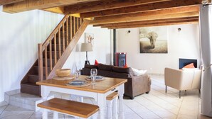 Amplia sala de estar con escalera de madera, una mesa de comedor con platos y vasos, un sofá y una silla.