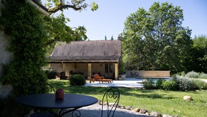 Una casa con un patio, mobiliario exterior y una piscina.