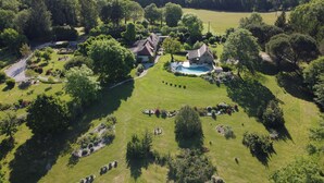 Vista aérea de una propiedad con piscina, varias casas y un césped bien cuidado.