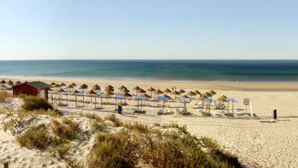 A beach with rows of umbrellas and sun loungers, a small building, and the ocean in the background. - LUXURY 4 BED VILLA WITH PRIVATE POOL NEAR BEACH AND GOLF ☀️ (Castro Marim)