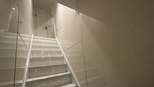 Eine Treppe mit Glastrennlämmern und einer Spiegelwand.