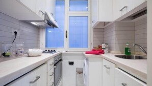 A compact kitchen with white cabinets, a window, a sink, and a stove.