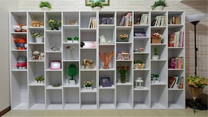 Une bibliothèque blanche agrémentée de divers objets décoratifs et de livres.