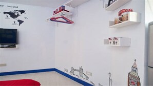Une pièce dotée d’un téléviseur à écran plat fixé au mur, d’un fauteuil rouge et d’étagères contenant divers objets.
