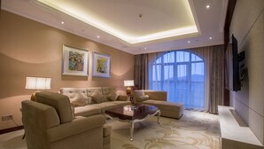 A spacious living room with a sectional sofa, a coffee table, and a large window with curtains. - Changzhou Joyland Gloria Grand Hotels (Changzhou)