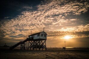 Un pontó de platja amb una torre de socorristes, una escala i l'oceà al fons durant el capvespre.