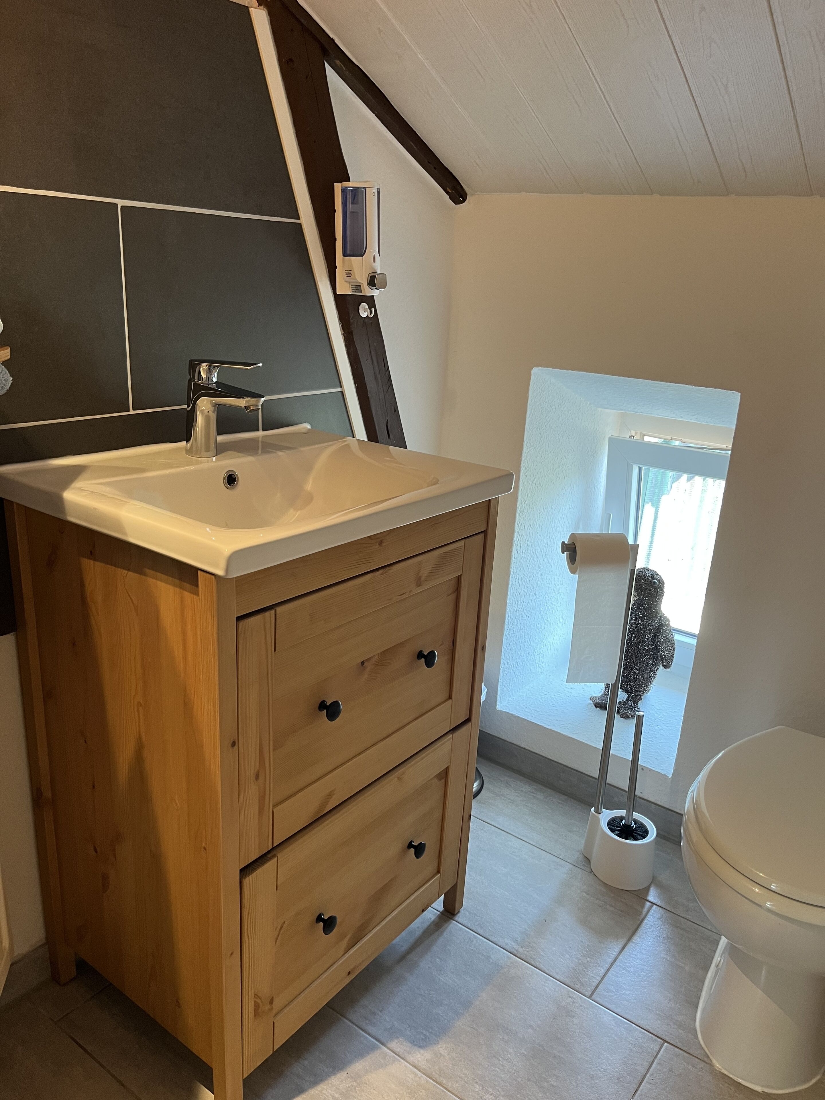 Une salle de bain avec un meuble-lavabo en bois, un lavabo blanc et des toilettes.